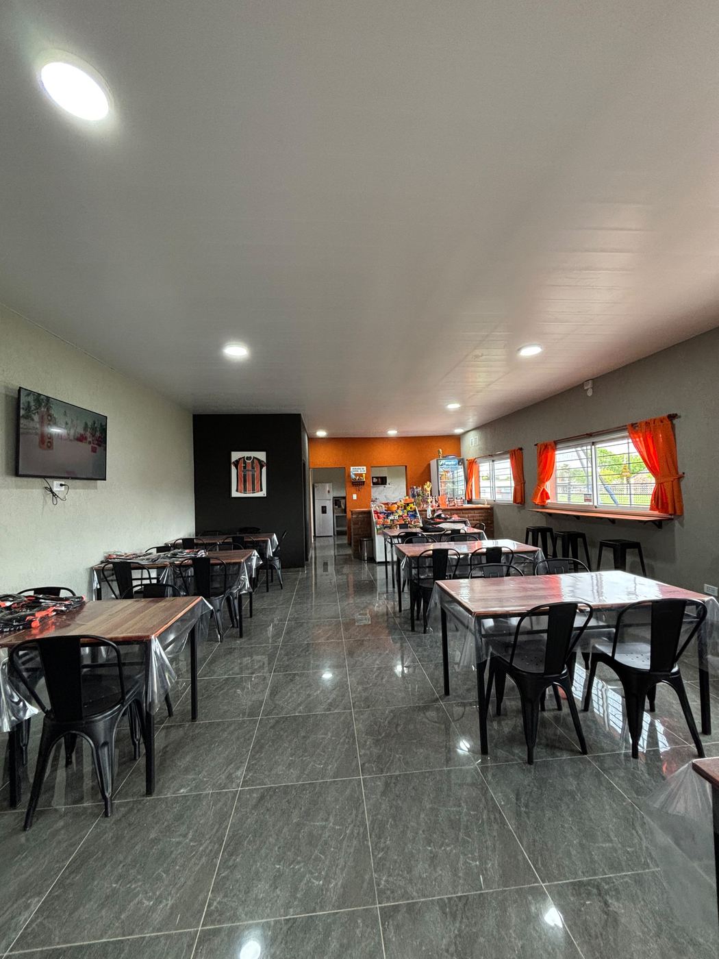 Salón del buffet con mesas, sillas y la barra al fondo