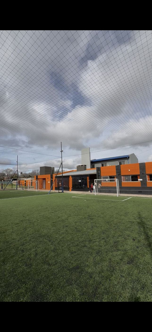 Cancha de fútbol 5 de césped sintético con el edificio del complejo al fondo